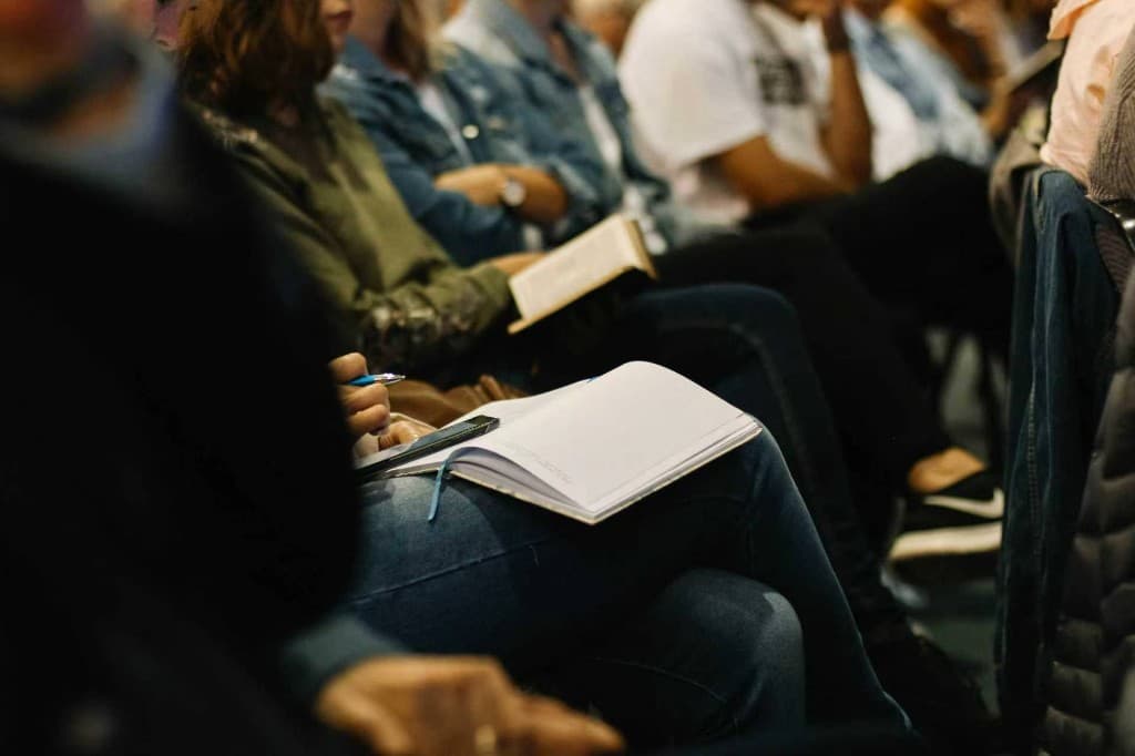Participants seated in a training session, taking notes in notebooks